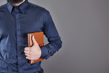 Portrait of toothy handsome bearded man with book on hands.の写真素材