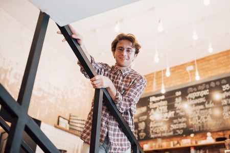 Thoughtful young man is sitting in confectionery shop. She is drinking coffee while waiting for someone.の写真素材
