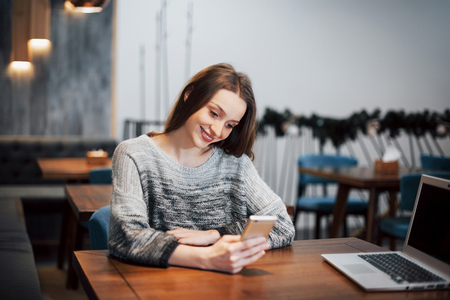 an attractive girl with long black hair ponders a new project during a coffee break sitting at a table in a coffee shop.の写真素材
