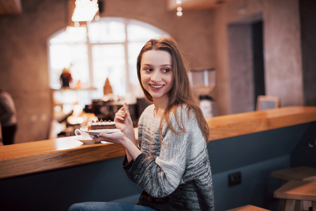 Smiling woman in cafe using mobile phone and texting in social networks, sitting alone.の写真素材