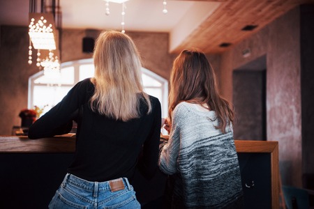 Two friends enjoying coffee together in a coffee shop as they sit at a table chatting.の写真素材