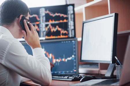 Stockbroker in shirt is working in a monitoring room with display screens. Stock Exchange Trading Forex Finance Graphic Concept. Businessmen trading stocks online.の写真素材