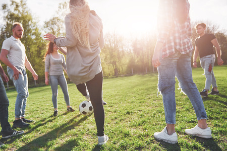 A group of friends in casual outfit play soccer in the open air. People have fun and have fun. Active rest and scenic sunset.の写真素材