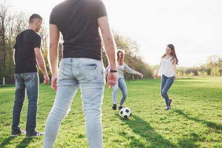 A group of friends in casual outfit play soccer in the open air. People have fun and have fun. Active rest and scenic sunset.の写真素材