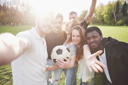 A group of friends in casual outfit do sephi on the soccer field. People have fun and have fun. Active rest and scenic sunset.の写真素材