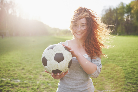 Young redhead sexy girl in casual player in soccer stadium at sunset.の写真素材
