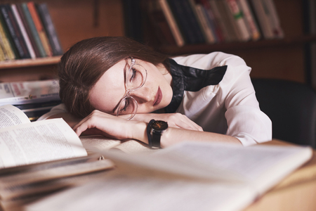 A young girl student is tired in the reading room of the old library.の写真素材