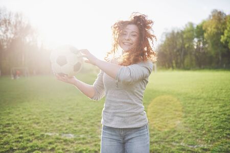 Young redhead sexy girl in casual player in soccer stadium at sunset.の写真素材