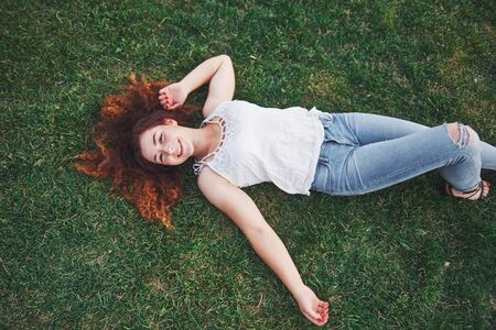 Relaxing girl with red, lying on the grass. Woman relaxes outdoorsの写真素材