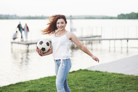 woman with a soccer ball, on a green grass near the water