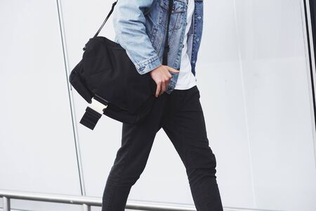 Young handsome man with a bag on his shoulder in a hurry to the airport.の写真素材