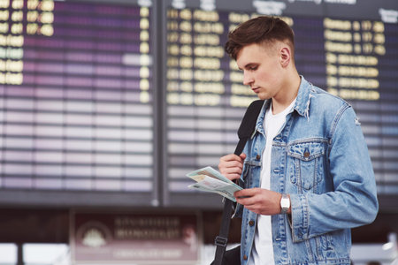 Young handsome man with a bag on his shoulder in a hurry to the airport.