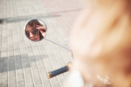 girl face in the scooters mirror on the streetの写真素材