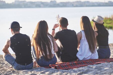 Happy friends have fun on the beach - Young people sitting in open air on summer holidays.の写真素材
