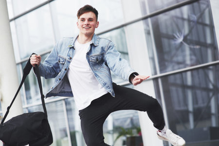Young handsome man with a bag on his shoulder in a hurry to the airport.