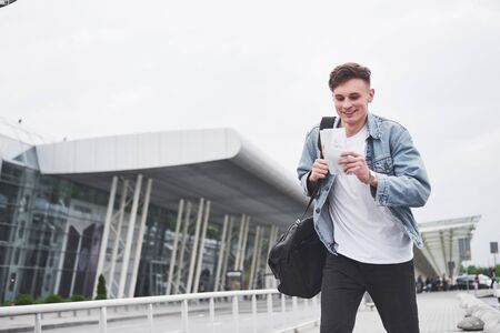 Young handsome man with a bag on his shoulder in a hurry to the airportの写真素材