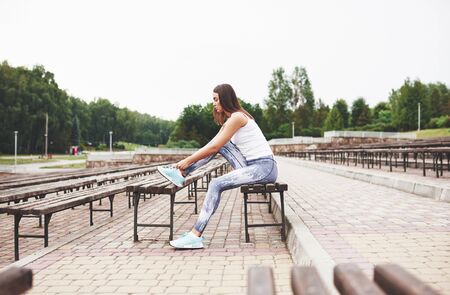 A beautiful athlete brunette performs outdoor exercises.の写真素材