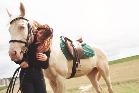 A happy girl communicates with her favorite horse. The girl loves animals andhorseback riding.の写真素材