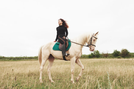 Young pretty girl - riding a horse, equestrian sport in spring time.