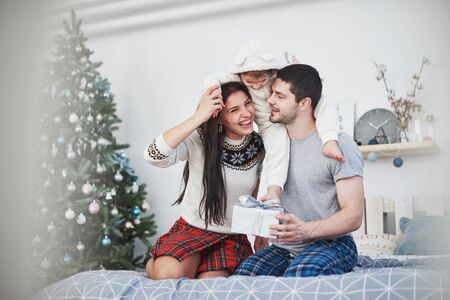 Happy family at christmas in morning opening gifts together near the fir tree. The concept of family happiness and well-being.の写真素材
