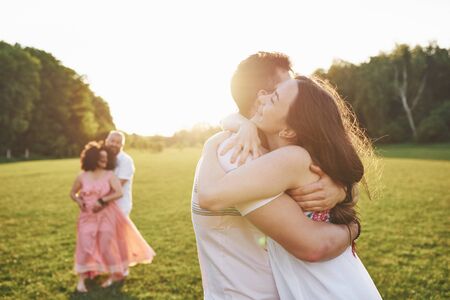 Two families of different generations embrace. Young husband and wife as well as their old parents who still love each other.の写真素材
