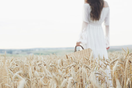 Young sensitive girl in white dress posing in a field of golden wheat.の写真素材