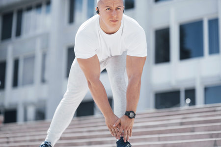 A handsome fitness man in a sportswear, doing stretching while preparing for serious exercise in the...