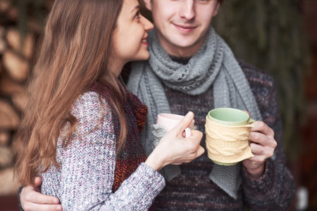 Young couple having breakfast in a romantic cabin outdoors in winter. Winter holiday and vacation. Christmas couple of happy man and woman drink hot wine. Couple in love.の写真素材