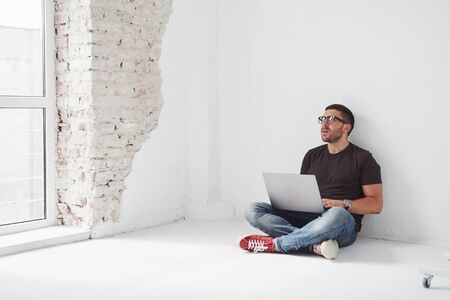 Handsome young man with laptop and check his timetable on white background.の写真素材