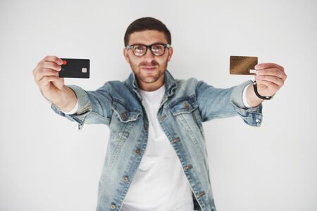 Young handsome male business executive in casual attire holding a credit card in the pockets on a white background. The concept of trading on the Internet and the ease of electronic money.の写真素材