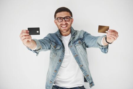Young handsome male business executive in casual attire holding a credit card in the pockets on a white background. The concept of trading on the Internet and the ease of electronic money.の写真素材