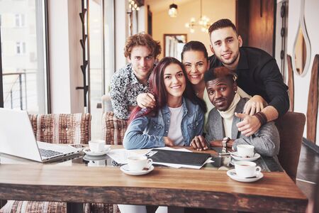 Friends having fun at restaurant. Three boys and two girls making selfie and laughing. On foreground boy holding smart phone. All wear casual clothes.の写真素材