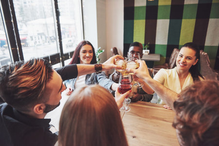 Hands of people with glasses of whiskey or wine, celebrating and toasting in honor of the wedding or...