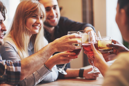 Hands of people with glasses of whiskey or wine, celebrating and toasting in honor of the wedding or...
