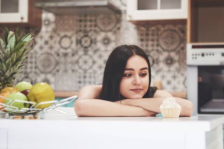 A beautiful sports woman with fresh fruits and vegetables in the kitchen.の写真素材