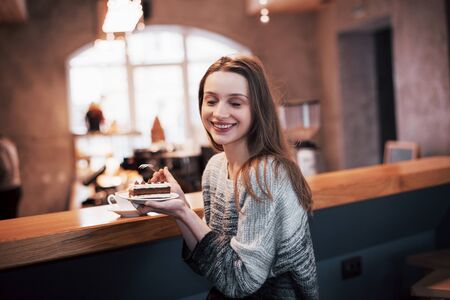 Happy smiling young woman using phone in a cafe. Beautiful girl in trendy spring colors.の写真素材