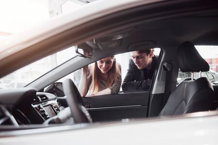 I like this car. Beautiful young couple standing at the dealership choosing the car to buy.の写真素材