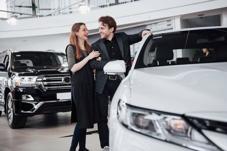 It is the one car I want! Beautiful young couple standing at the dealership choosing the car to buy.の写真素材