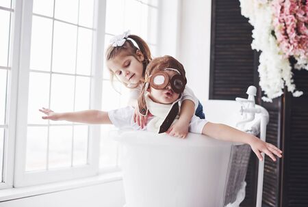 Portrait of a girl and a boy in pilot hat playing in bathroom at pilots or sailors. The concept of travel, childhood and the realization of dreams.