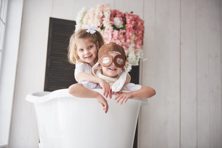 Portrait of a girl and a boy in pilot hat playing in bathroom at pilots or sailors. The concept of...