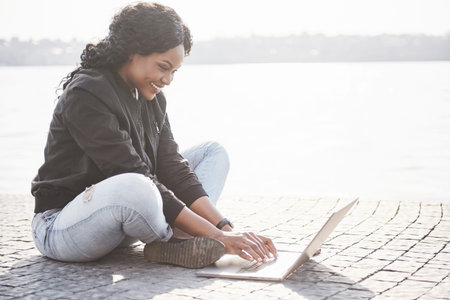 Young woman on the street working on laptop.