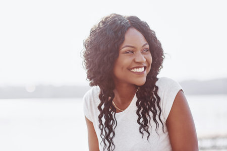 Portrait of smiling young black woman with sunlight flare.の写真素材