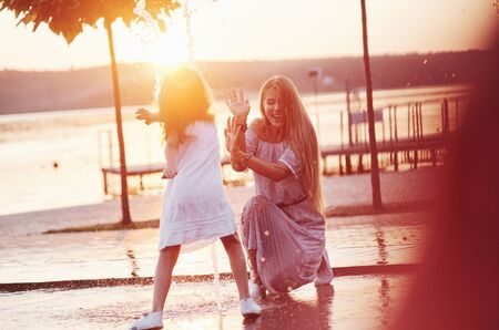 Water games. In a hot sunny day mother and her daughter decide to use fountain for cooling themselves and have fun with it.の写真素材