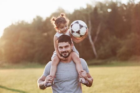 Pure happiness. Photo of dad with his daughter at beautiful grass and woods at background.の写真素材