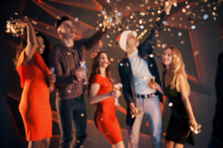A group of friends are having fun in beautiful chiffon dresses with champagne and confetti,...