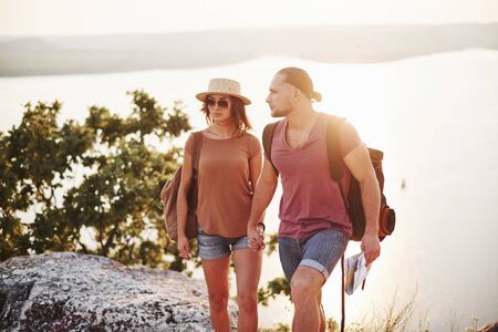 Young couple have decided to spend their holiday in active way on the edge of the gorgeous rock with lake at background.の写真素材