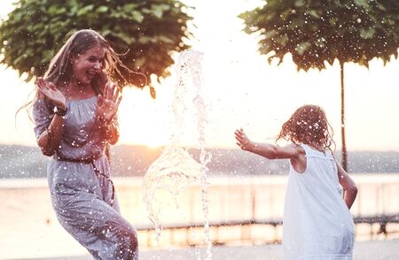 Happiness, frozen in time. In a hot sunny day mother and her daughter decide to use fountain for cooling themselves and have fun with it.の写真素材