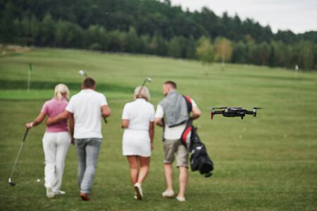 Group of stylish friends on the golf course learn to play a new game. Shooting is conducted from the quadrocopter droneの写真素材