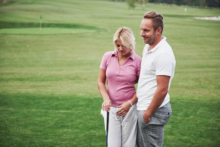 Sportive couple playing golf on a golf course, they stand to the next hole.の写真素材