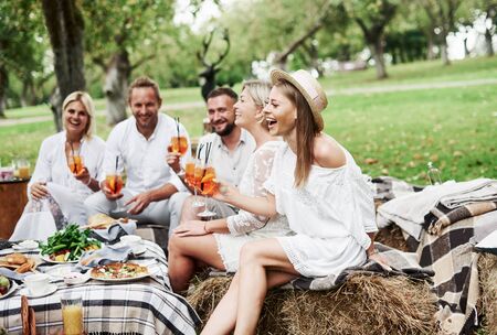Carefree mood. Group of adult friends have a rest and conversation in the backyard of restauraunt at dinner time.の写真素材